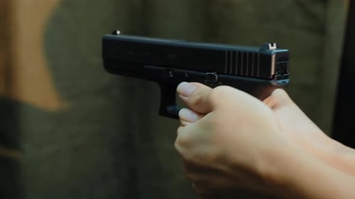 Female Hands Holding Pistol Ready Shoots To Target, Close-up
