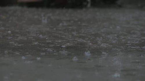 Close-up Drops of Summer or Autumn Rain of Water Fall on Asphalt in the City Turning Into a Large