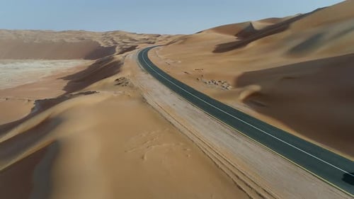 Aerial view of white car in clean road in the desert, Abu Dhabi, UAE.