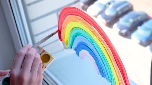 Painting a Bright Rainbow on a Window Indoors