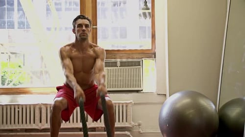 Man Doing Battle Rope Squats at Gym