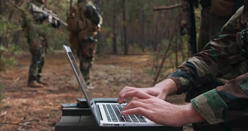 Military Operation: Camouflage Uniforms Using Laptop in Wilderness