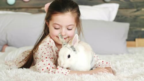 Girl Cuddling Rabbit on Bed
