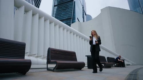 Woman Walks Using Phone in Modern Urban Setting