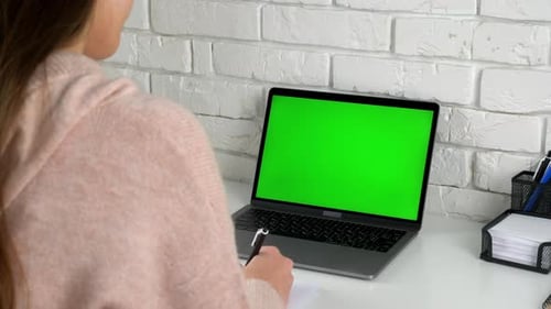 Woman Writing in Notebook with Laptop Green Screen