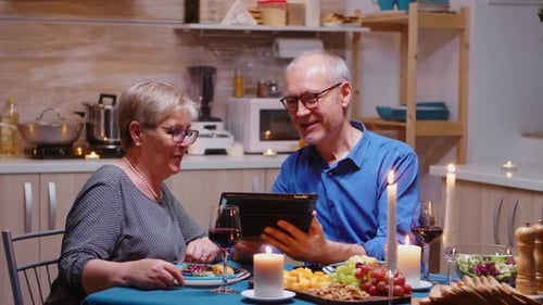 Couple Viewing Tablet During Candlelit Dinner at Home