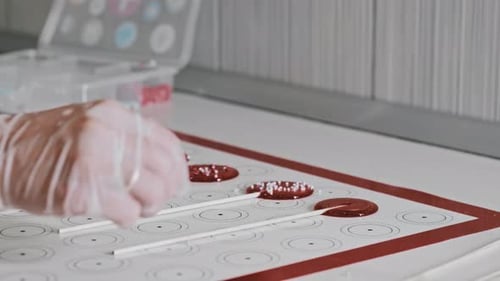 Chef Making Red Homemade Sugar Lollipops and Pouring Sprinkling Over It