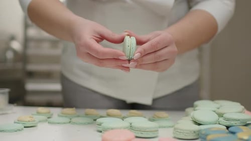 Female chef's hands cooking mint macaron cookies.