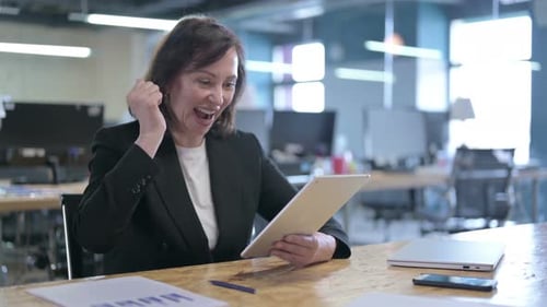 Successful Middle Aged Businesswoman Celebrating While Working on Tablet