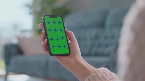 Smartphone with Green Screen Held in Hand Indoors