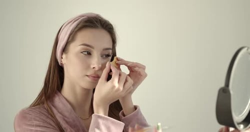 Woman Applies Gold Eye Mask in Mirror