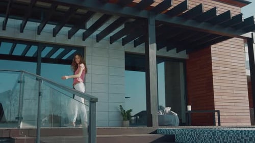 Hermosa mujer invita a casa de lujo. Llamada de mujer morena para entrar en casa