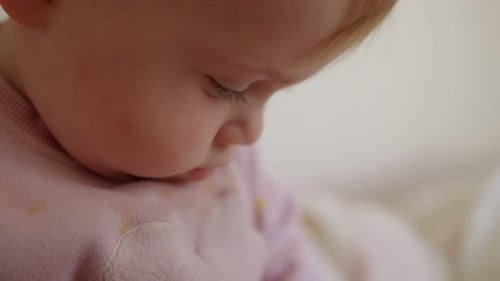 Cute baby sitting on a bed, playing, rolling and laughing