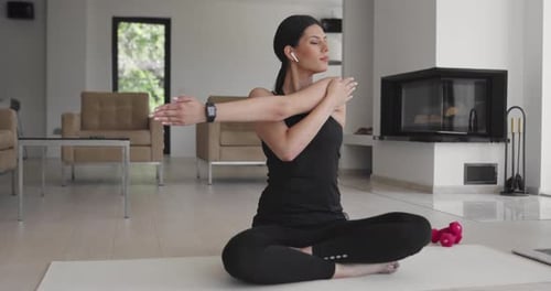Woman Stretches Shoulders at Home on Yoga Mat