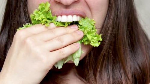 pretty happy woman girl putting salad leaf lettuce in mouth. healthy food, nutrition concept, weigh
