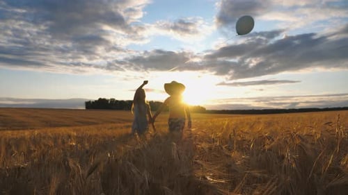 Couple of Cute Little Kids Holding Hands of Each Other Going Among Barley Plantation at Sunset