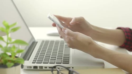 Hands Using Mobile Phone with Laptop and Plant