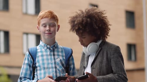 Two Boys Using Phones in the City