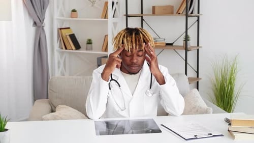 Stressed Doctor Massaging Temples in Office