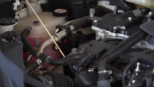 Hand eines Technikers, der den Ölstand am Ölmessstab eines Automotors überprüft