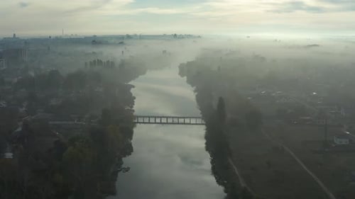 Beautiful morning, summer flight over the river. The bridge over the river in the fog, at dawn.