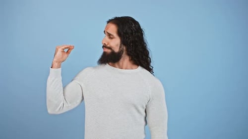 Studio-Porträt eines skeptischen bärtigen Kerls, der Blah Blah Geste zeigt, die mit seiner Hand spricht