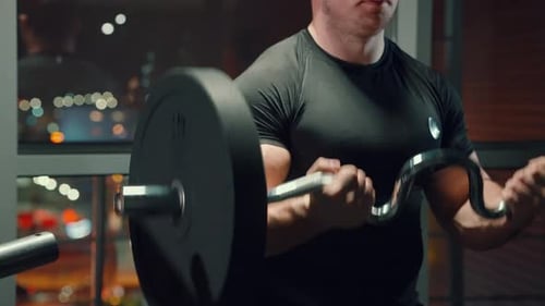 Bodybuilder Lifting Barbell City Lights Behind Window