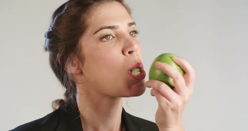 Woman eating an apple on a white studio background