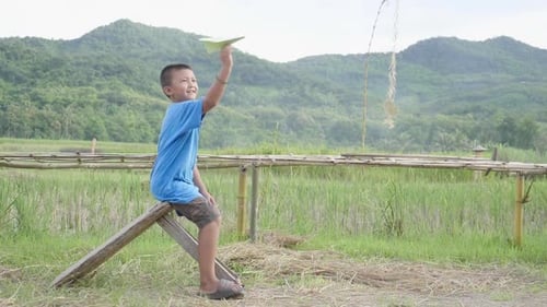 Boy With Paper Airplane in Rural Landscape
