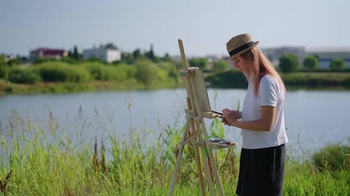 Woman Painting Outside on Easel by the Lake