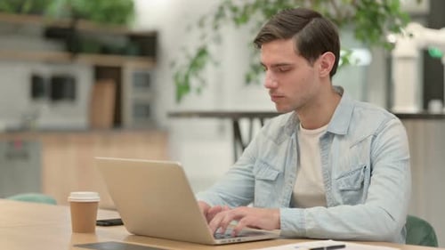 Young Adult Typing on Laptop in Modern Office