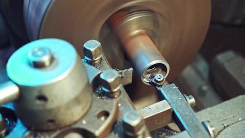 Bei der Bearbeitung eines Teils auf der Drehmaschine in der Produktion fallen Metallspäne auf den Boden.