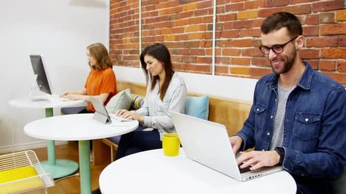 Young Adults Working on Laptops in Modern Office