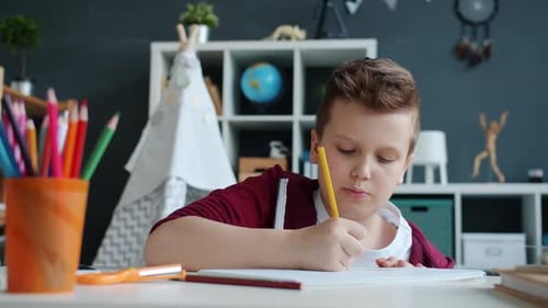 Young Boy Drawing with Colored Pencils at Table