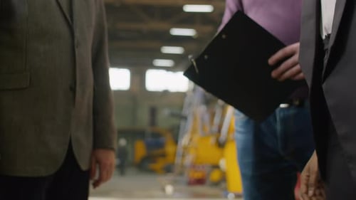 Female Engineer Greeting Colleagues with Handshake in Factory