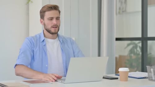 Man Frustrated Using Laptop at Desk