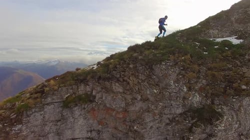 Vue aérienne d'un coureur de trail remontant la crête d'une montagne enneigée
