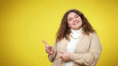 Woman Smiling and Pointing on Yellow Background