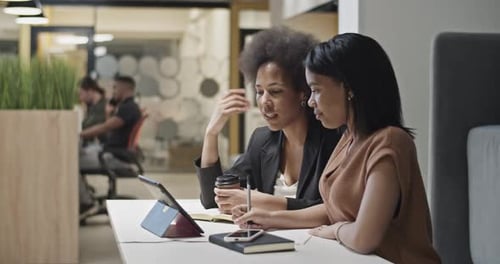 Two Women Collaborating on Tablet in Office