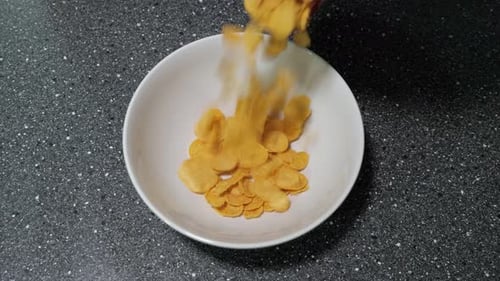 Dry Cereal Pouring into a White Bowl