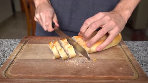 Man Slicing A Classic Cuban Bread With Knife On Wooden Chopping Board. - close up