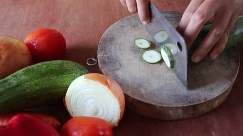 Person Cutting Zucchini on Wood Board with Vegetables