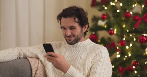 Man Using Phone by Christmas Tree