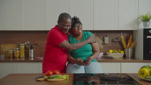 Happy Couple Enjoys Mobile Phone in Bright Kitchen