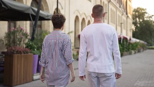 Back View Loving Young Caucasian Couple Walking in Slow Motion on City Street Talking