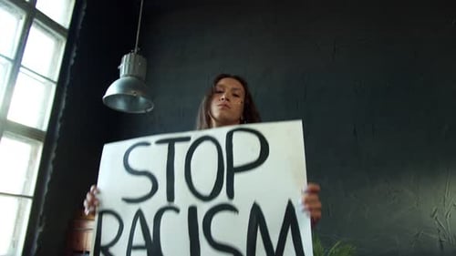 Woman Holds Stop Racism Sign in Bright Studio