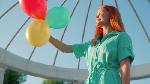 Girl Holding Balloons Outside on a Sunny Day