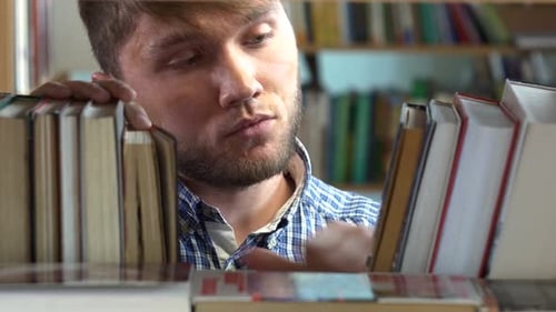 Young Man Browsing Through the Racks of Books in a Library