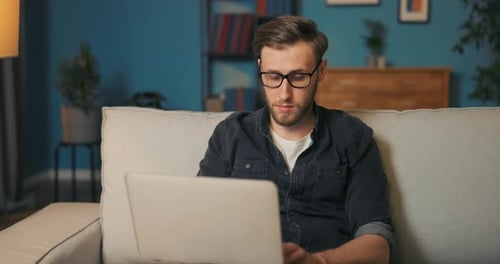 Man Working on Laptop on Couch at Home