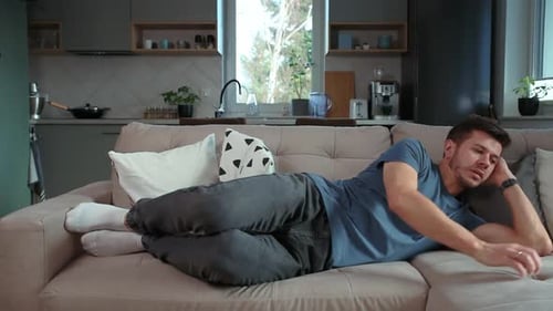 Man Lounging on a Couch Watching Television